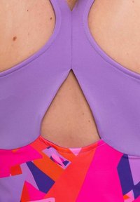 Top da bagno viola con taglio a chiave sulla schiena. La parte inferiore presenta un motivo geometrico colorato in tonalità di rosa, arancione e blu.