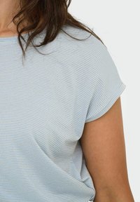 Top de color azul claro con sutiles rayas verticales y una textura suave. Presenta un cuello redondo y mangas cortas enrolladas. Ajuste cómodo.