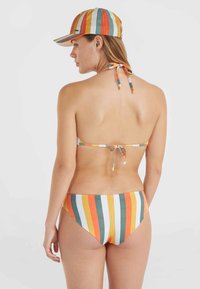 Bikini a rayas y gorra en naranja, amarillo, verde y azul. El bikini cuenta con tiras delgadas y un diseño con lazo en la parte posterior. Textura suave, estilo ajustado.