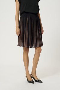 Jupe plissée noire avec un design texturé, dotée d'une large ceinture élastique et de couches transparentes, associée à des talons slingback noirs.