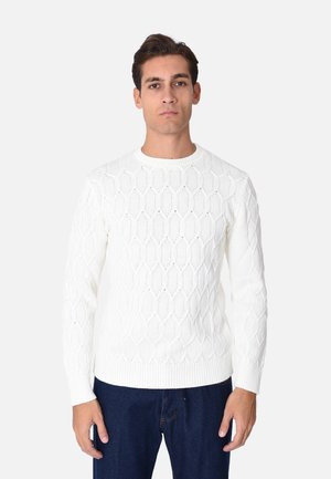 Maglione bianco lavorato a maglia con un motivo a diamante testurizzato, maniche lunghe, collo rotondo e polsini e orlo a costine, indossato con jeans blu.