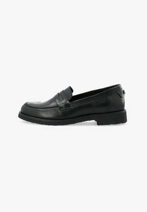 Black leather loafers with a smooth finish, rounded toe, raised stitching, and a textured rubber sole. Accented with a decorative strap.