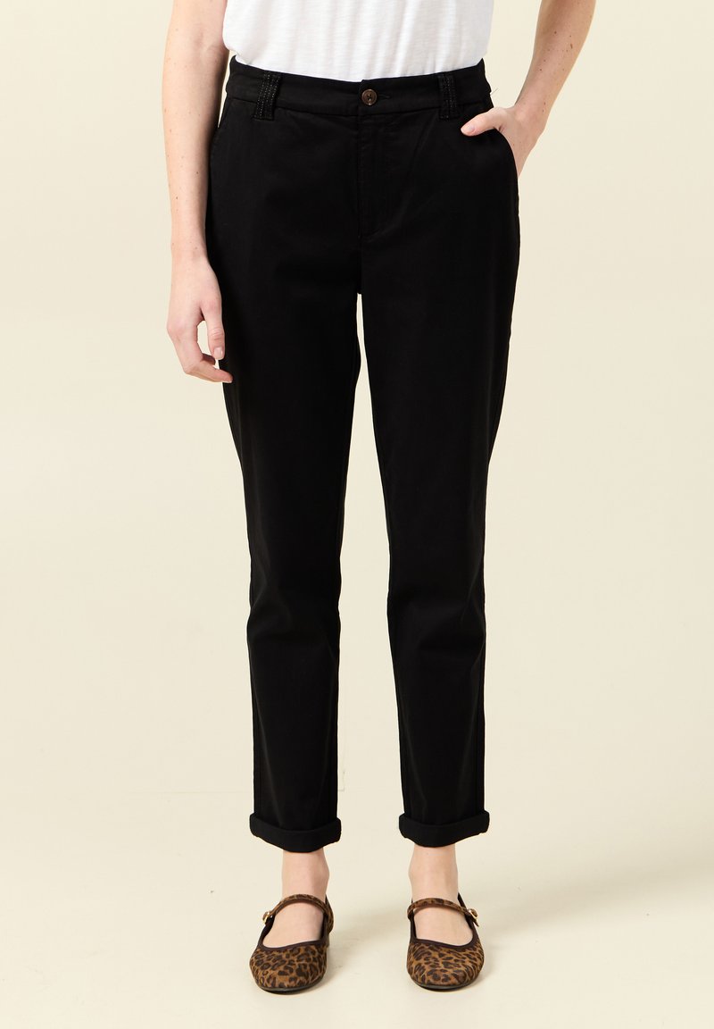 Czarne, podwijane chinosy z zapięciem na guzik i bocznymi kieszeniami. Wykonane z tkaniny tkanej, o prostym kroju nogawek. Brązowy guzik jako akcent.
