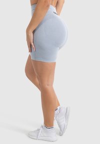 Lichtblauwe, hoge shorts met gestructureerde details, een aansluitend ontwerp en een gladde afwerking, gecombineerd met witte sportschoenen.