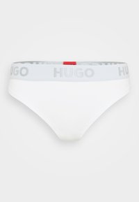 Culottes blanches pour femmes avec une ceinture élastique grise arborant le logo "HUGO" et une petite étiquette rouge à l'arrière. Tissu doux et texture lisse.