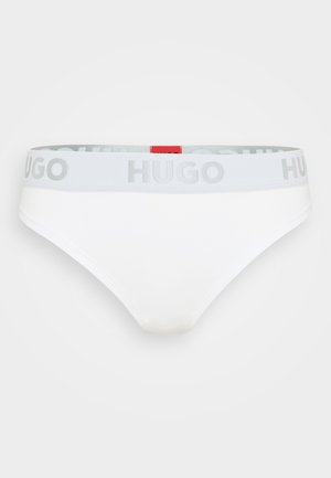 Baltos moteriškos kelnaitės su pilkos spalvos elastinga juostele, kurioje yra "HUGO" logotipas, ir maža raudona etikete gale. Minkšta medžiaga ir glotni tekstūra.
