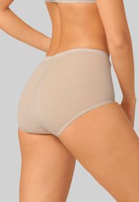 Mutandine hipster beige da donna senza cuciture, con una texture morbida e liscia e un elastico sottile in vita, che mostrano un design a copertura totale.