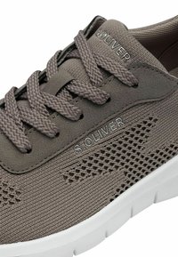 Scarpa sportiva grigia con tomaia in tessuto testurizzato, lacci intrecciati e suola in gomma bianca. Presenta il logo "S.OLIVER" sulla linguetta e sul lato.