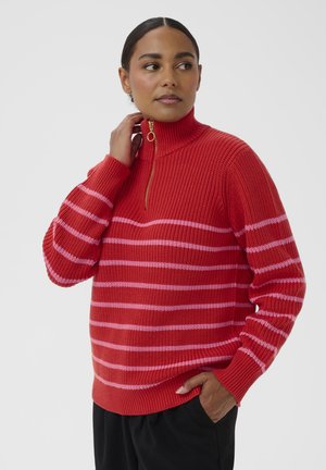 Red striped sweater with a high collar, featuring pink horizontal stripes and a gold zipper detail. Waffle knit texture throughout.