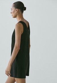 Czarna sukienka bez rękawów o prostej sylwetce, wykonana z gładkiej tkaniny. Posiada zamek błyskawiczny z tyłu i minimalistyczny design.