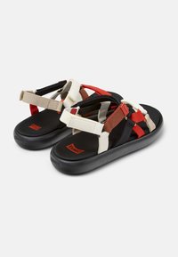 Multicolored sandals featuring a mix of straps in red, black, brown, and cream. The soles are black with textured rubber for grip.