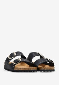 Sandalias de cuero negro con dos correas ajustables con hebillas, detalles de tachuelas, plantilla de corcho y suela de goma texturizada.