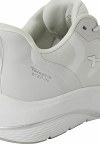 Sneaker bianca con tessuto testurizzato e colletto imbottito. Caratterizzata da un marchio in argento "Tamaris STEP-IN" e una suola in gomma spessa con un design ondulato.