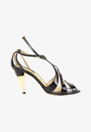 Sandale à talon haut en cuir verni noir avec talon conique doré et panneaux transparents, dotée d'une bride de cheville avec boucle.