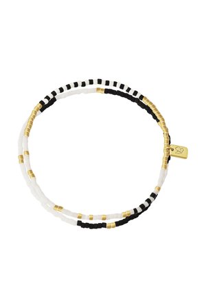 Bracelet double rangée de perles alternant perles noires, blanches et dorées, avec un petit pendentif rectangulaire en or gravé d'un cœur.