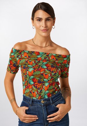 Bluzka z dekoltem odsłaniającym ramiona ozdobiona kwiecistym wzorem w żywych kolorach pomarańczy, zieleni i niebieskiego na ciemnym tle, wykonana z elastycznego materiału, zestawiona z wysokim stanem jeansów.