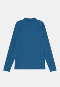Camisa de manga larga en tejido azul sólido con un cuello alto, que presenta un diseño de espalda sin costuras y mangas ajustadas. Textura suave en general.