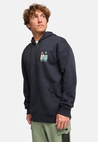 Sudadera con cremallera de color navy con un estampado gráfico que presenta palmeras y una escena de playa. Tiene ajustes con cordón y bolsillos frontales.