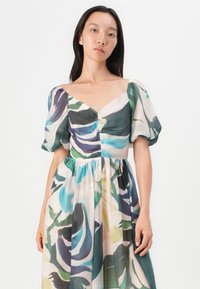 Kleid mit Blumenmuster aus leichtem Stoff, mit Volantärmeln, V-Ausschnitt und geraffter Taille. Die Farben umfassen Grün, Blau und Rosa.