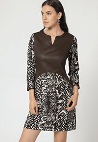 Vestido en blanco y negro con un corsé de cuero marrón, mangas de tres cuartos con estampado y diseños geométricos en la falda.