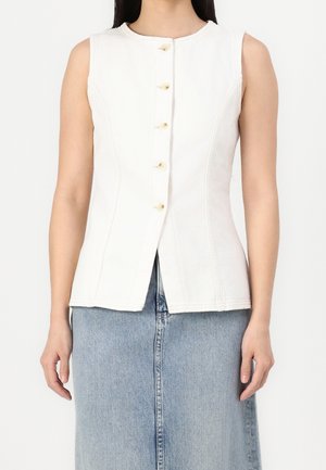 Biała kamizelka z denimu bez rękawów, z okrągłym dekoltem, sześcioma guzikami z przodu i dopasowanym krojem, zestawiona z niebieską spódnicą z denimu.