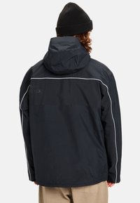 Zwarte waterdichte jas met capuchon, voorzien van witte bies langs de schouders en rug, gemaakt van glad, duurzaam materiaal.