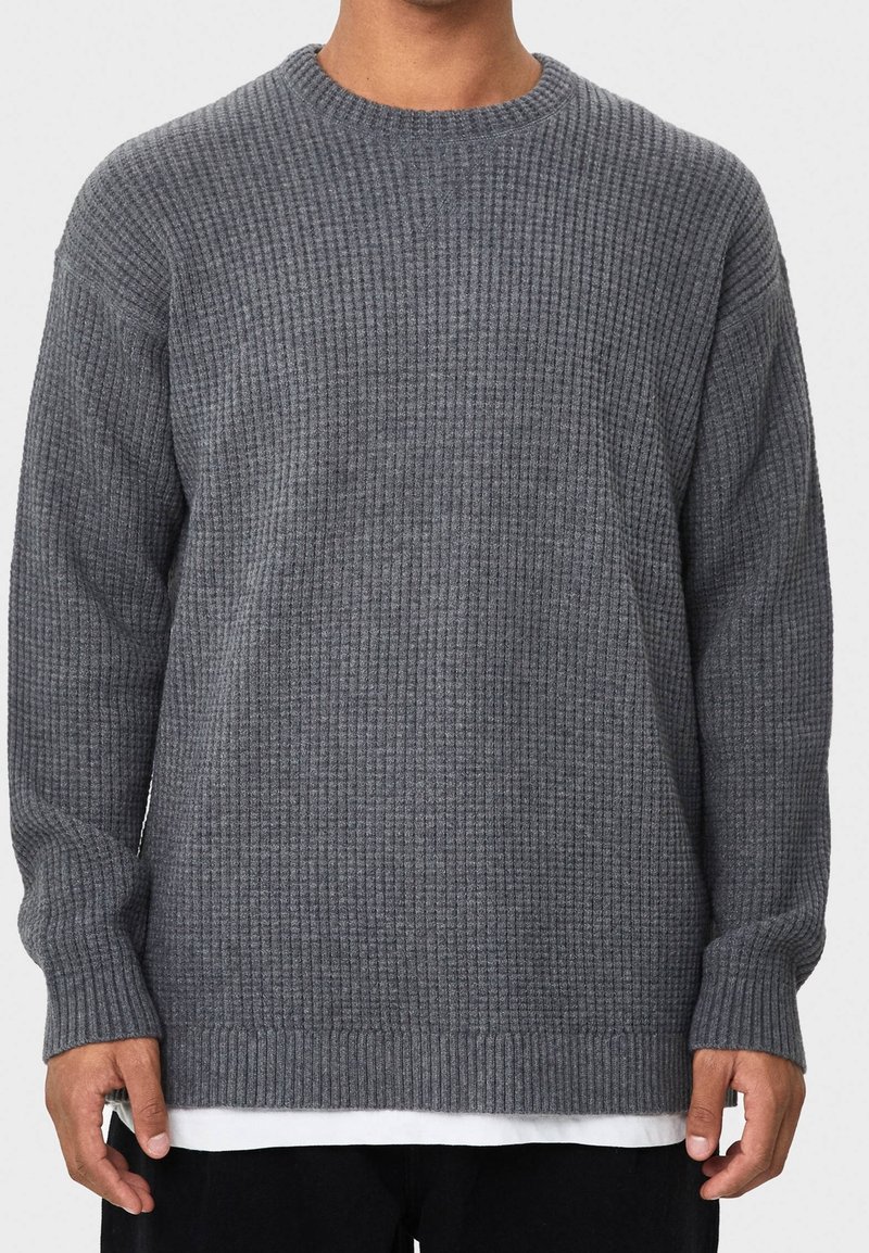 Grauer gerippter Rundhalspullover mit langen Ärmeln, einem strukturierten Muster, lockerer Passform und einem Saum, der über die Taille hinausgeht.