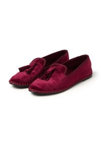 Scarpe slip-on in velluto borgogna con dettaglio a nappe, dotate di bordo cucito e suola piatta. Texture liscia, design minimalista.