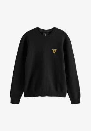 Czarny sweter z okrągłym dekoltem i długimi rękawami, z małym żółtym herbem harfy na lewej piersi.