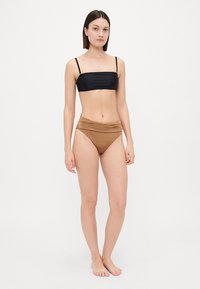 Kétrészes bikini szett, fekete bandeau felsővel és barna magas derekú alsóval, sima anyagból, redőzött részletekkel.