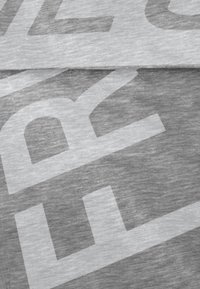 Grijs t-shirtstof met een groot, lichtgrijs bedrukt tekstpatroon. De textuur lijkt zacht, met een gladde en licht gemêleerde afwerking.