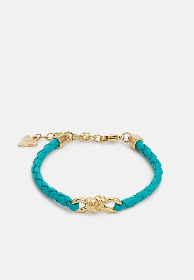 Bracelet en cuir turquoise tressé avec un nœud doré en centre, chaîne réglable, fermoir mousqueton et breloque triangulaire.