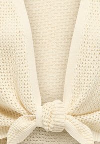 Cardigan en maille crème présentant un motif texturé, un devant ouvert et un détail noué à la taille. Matière douce et légère.