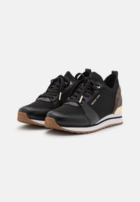 Black athletic sneakers featuring a mix of mesh and leather, gold accents, and a textured pattern on the heel; white and brown sole.