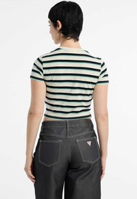 Gestreepte cropped t-shirt in lichtgroen met donkere strepen, gecombineerd met donkere denim jeans. Het shirt heeft korte mouwen en een getailleerd design.