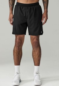 Black athletic shorts with an elastic waistband, smooth fabric, knee-length design, and a small logo accent on the lower left side.
