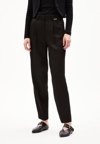 Black tailored trousers with a smooth, shiny texture, featuring sharp creases and a slim fit. Includes a subtle brand tag at the waistband.