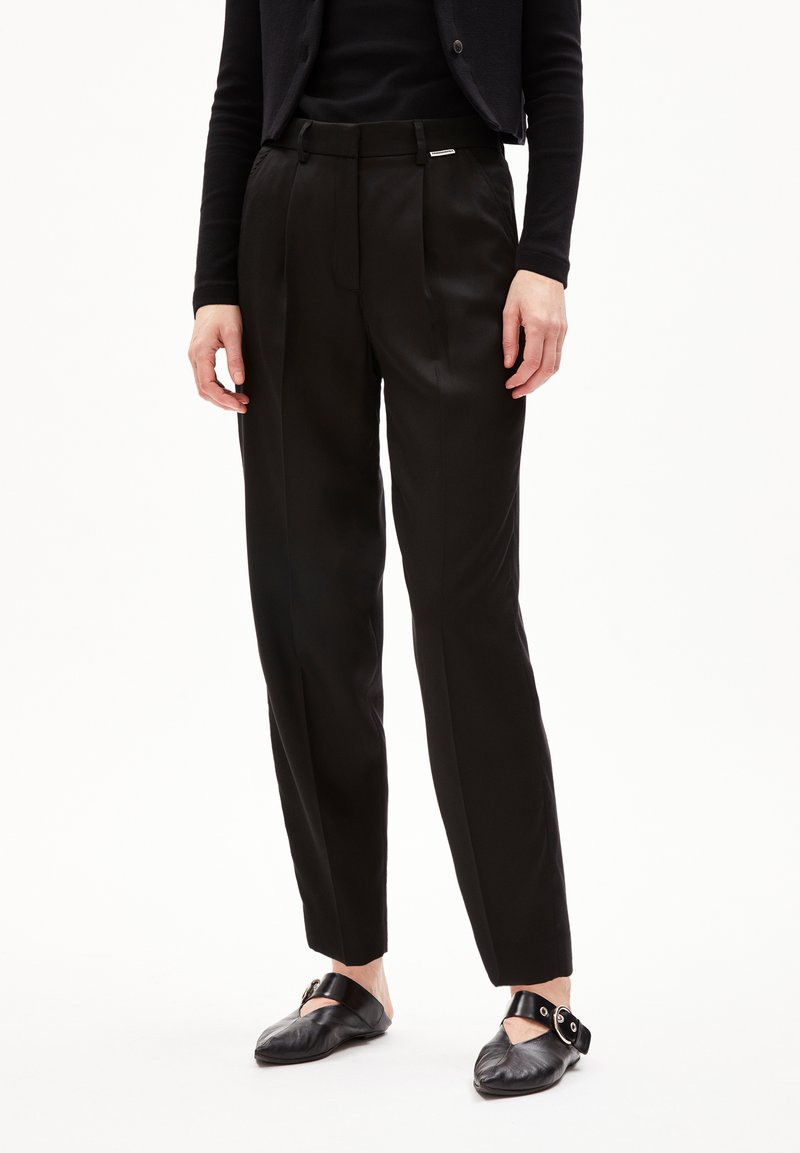 Zwarte tailleurbroek met een gladde, glanzende textuur, voorzien van scherpe vouwen en een slim fit. Inclusief een subtiele merketiket aan de tailleband.