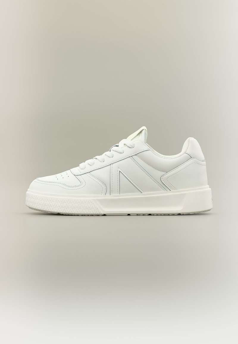 Biela nízka teniska s predným viazaním na šnúrky, hrubou textúrovanou podrážkou a dizajnom zošitej panely, zobrazená z profilu na neutrálnom pozadí.