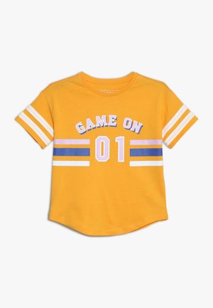 Gele korte mouwen T-shirt met witte strepen op de mouwen, paarse en blauwe strepen op de borst en "GAME ON 01" op de voorkant gedrukt.