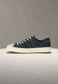 Pantof sport negru cu partea inferioară joasă, șireturi albe, vârf din cauciuc alb și talpă groasă albă, pe o suprafață și un fundal neutru.