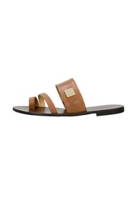 Sandalo in pelle marrone con due ampie cinghie e un accento metallico quadrato. Sole piatto con un design minimalista e texture liscia.