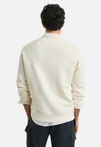 Lichtbeige sweatshirt van gestructureerde stof, met een ronde hals, geribbelde mouwen en een ontspannen pasvorm, gezien van de achterkant.