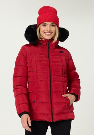 Red puffer jacket with a zip closure, black faux fur-lined hood, and vertical quilted pattern. Paired with a matching knit beanie.