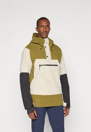 Vihreä ja kerma värilohkottu takki, jossa on huppu, etupainonappikiinnitys, vetoketjullinen rintatasku ja mustat hihat, joissa on tarranauhat.