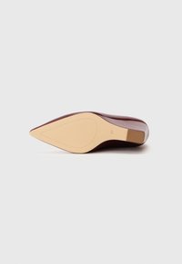 Chaussure à talon haut bordeaux avec un bout pointu et une finition lisse ; dotée d'une semelle en caoutchouc beige et d'un design épuré et minimaliste.