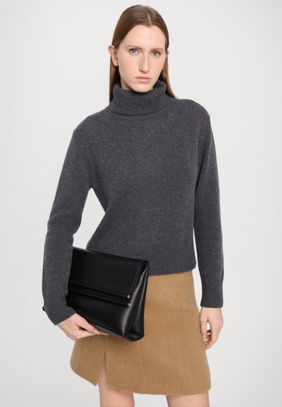 Gray knit turtleneck sweater paired with a tan fur skirt. Model holds a black leather clutch with two gold accents. Simple and modern design.