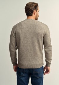 Gray knit sweater with long sleeves and ribbed hem, paired with blue jeans. The fabric appears soft and textured, with a subtle pattern.