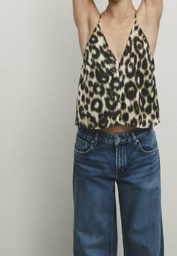 Haut en jersey à imprimé léopard avec un décolleté en V profond, fait de tissu léger ; associé à un jean bleu en denim ample.