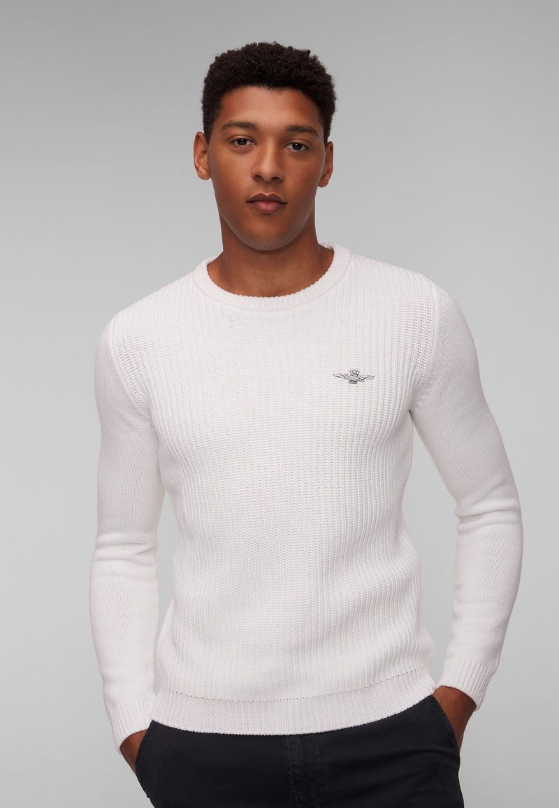 Maglione bianco a coste con scollatura rotonda e maniche lunghe. Presenta un discreto logo blu sul lato sinistro del petto.